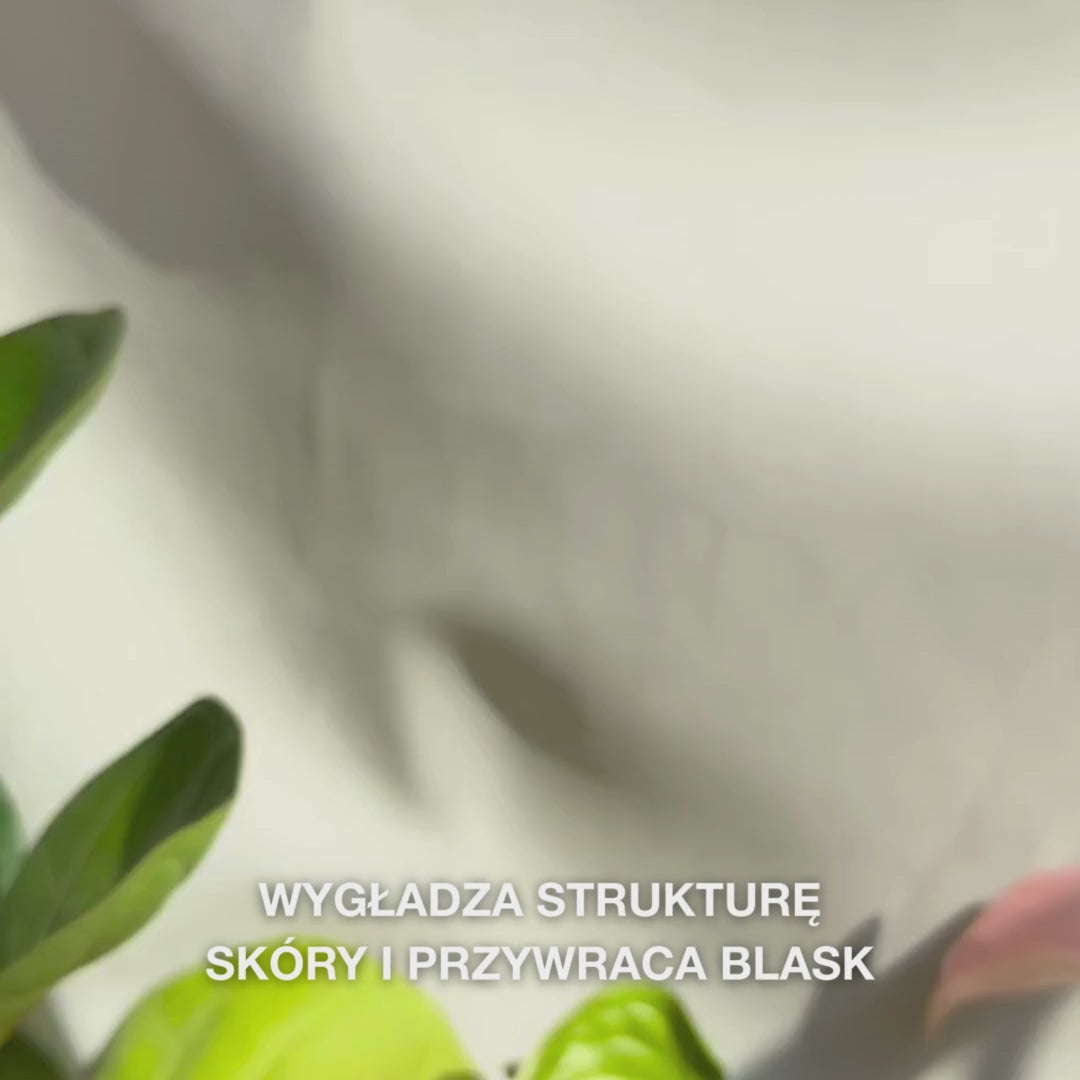 Zbliżenie na dłoń nanoszącą kilka cienkich kropli przezroczystego, lekkiego Peeling Serumu na opuszki palców, a następnie delikatnie wmasowując go w czystą skórę twarzy — jedwabista, płynna konsystencja widocznie usuwa martwe komórki, wygładza strukturę skóry i podkreśla blask dzięki naturalnym AHA (Lime Pearl), niacynamidowi i olejkowi z drzewa herbacianego 
