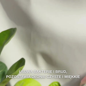 Zbliżenie na dłonie, które dozuje przezroczysty, jasnoniebieski, pieniący się płyn do mycia rąk z olejkiem z drzewa herbacianego do dłoni, a następnie delikatnie rozprowadza go po wnętrzu dłoni, wierzchu i między palcami — delikatna pianka oczyszcza bakterie i brud, jednocześnie zmiękczając i nawilżając skórę.