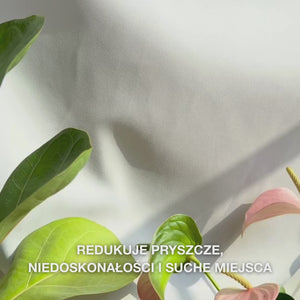 Zbliżenie na dłoń dozującą niewielką ilość lekkiego, kremowego balsamu do ciała z kwasem salicylowym na dłoń i wmasowującą go w szorstką, skłonną do niedoskonałości skórę: jego gładka, szybko wchłaniająca się formuła delikatnie złuszcza martwy naskórek, nawilża kwasem hialuronowym i mlekowym oraz wygładza strukturę skóry dzięki kwasowi salicylowemu i niacynamidowi.